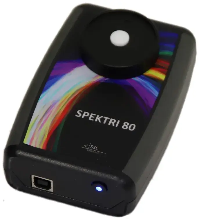 Musta Spektri 80 -spektrometri, jossa on värikäs kuvio ja valkoinen ympyrä päällä, USB-portti ja sininen valo.